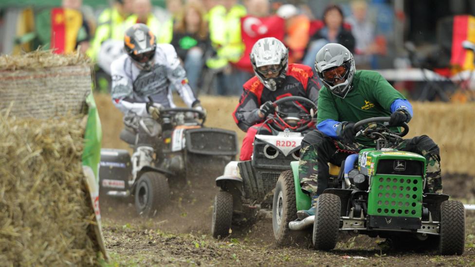 Three lawnmower racing drivers competing in a sit on lawnmower race.