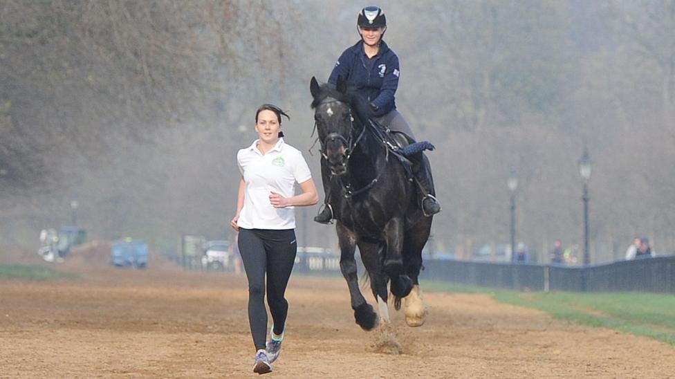 A woman is being pursued by a woman on horseback in the man vs horse race in Wales.