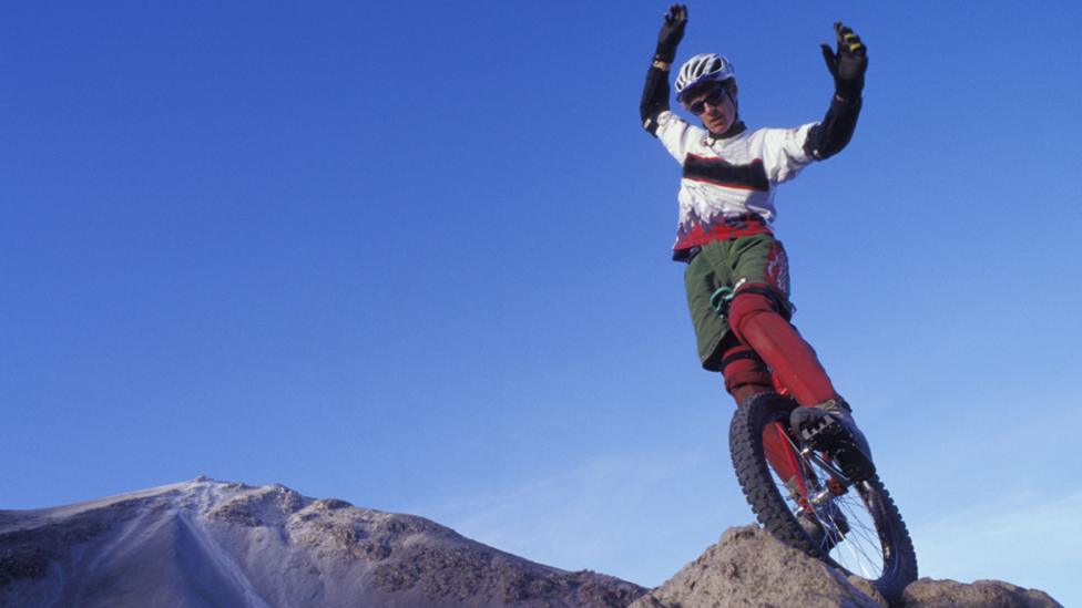 A mountain unicycle racer at the top of a mountain.