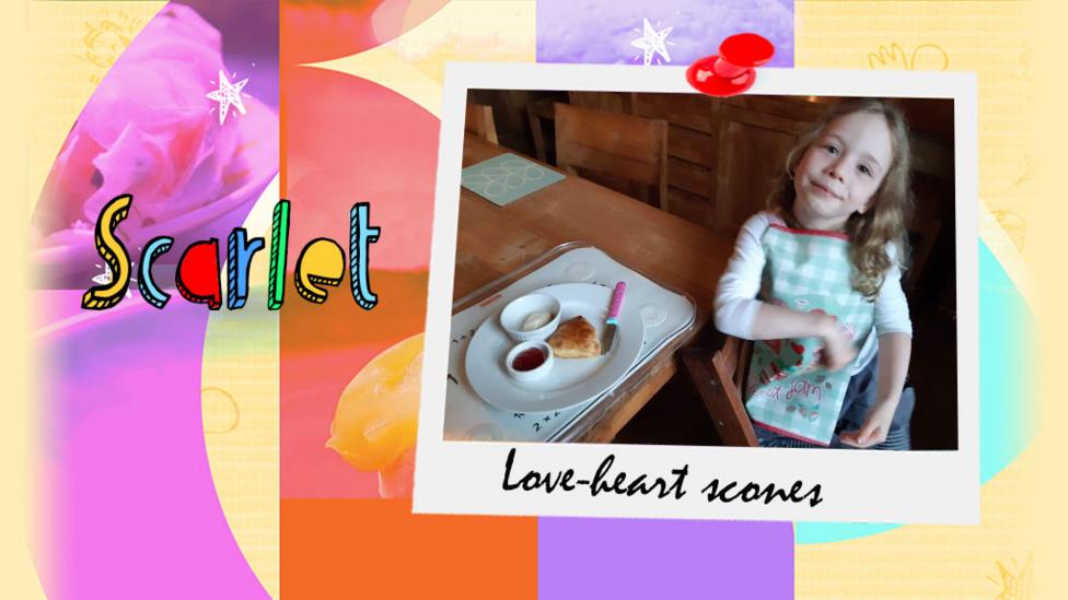 A girl holds the scones in the shape of love hearts that she has made.