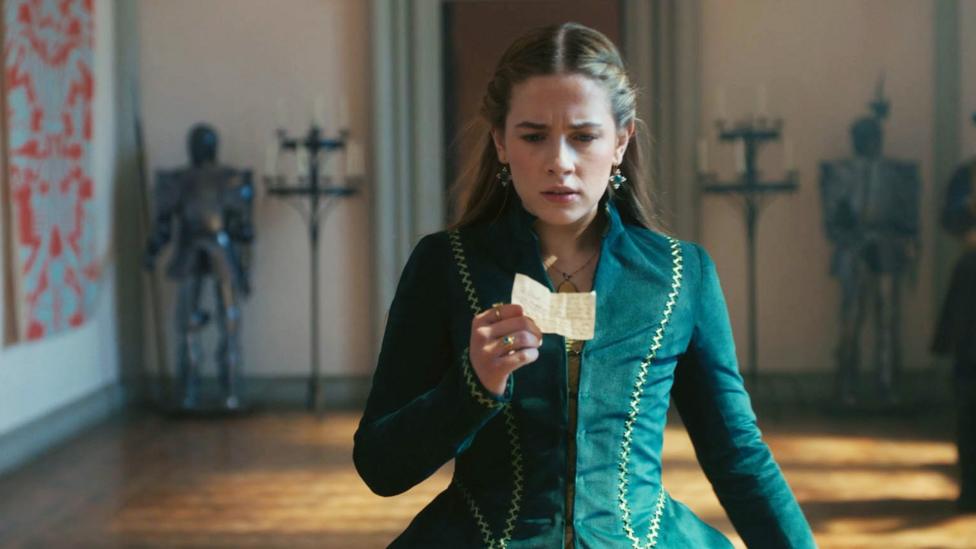 Image of Lady Grace looking at a piece of paper.