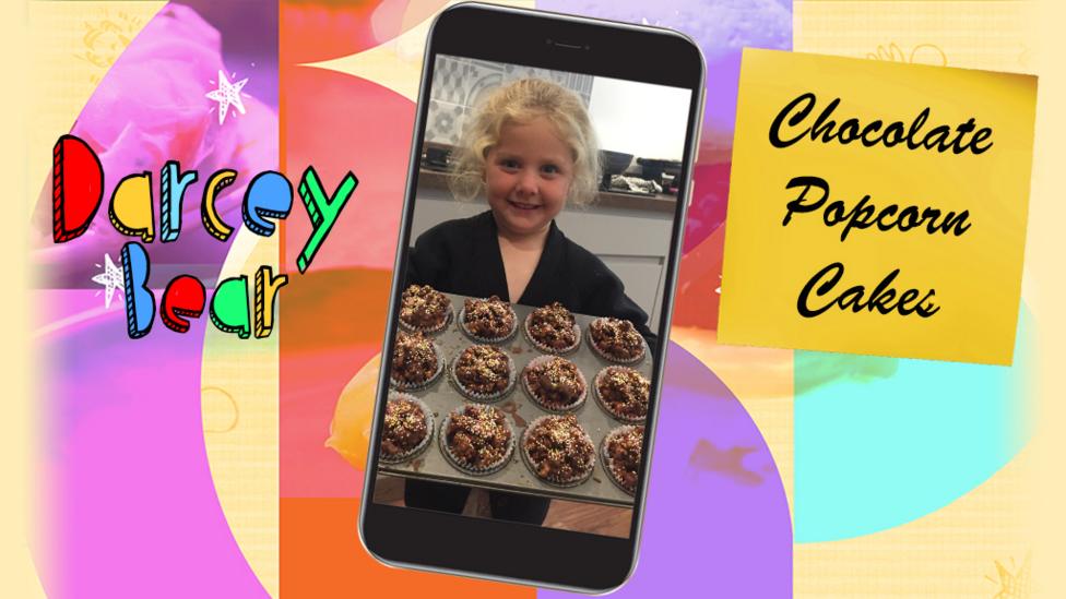 A girl called DarceyBear holding a tray of muffin cases filled with chocolate popcorn cakes.