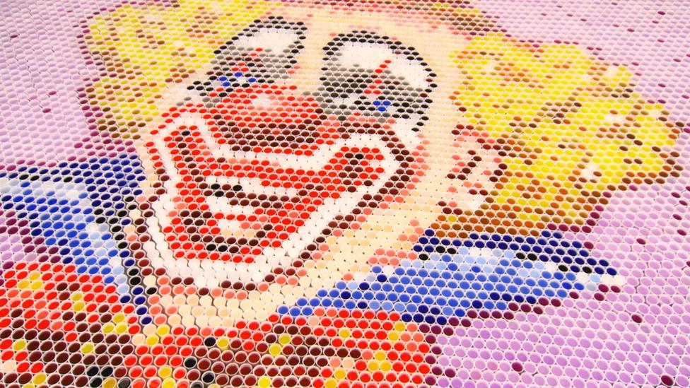 Clown image made out of cups of coloured water.