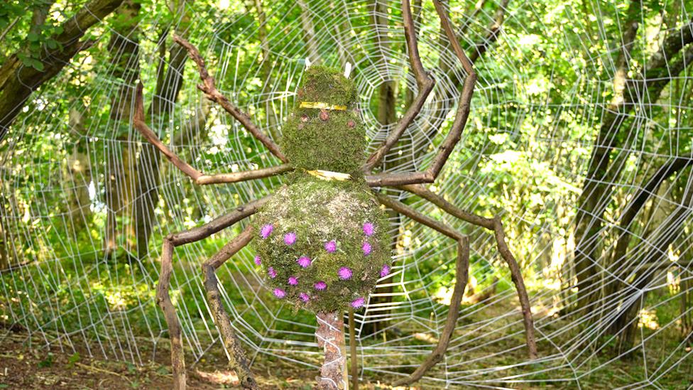 Giant spider and web created in a forest with sticks.