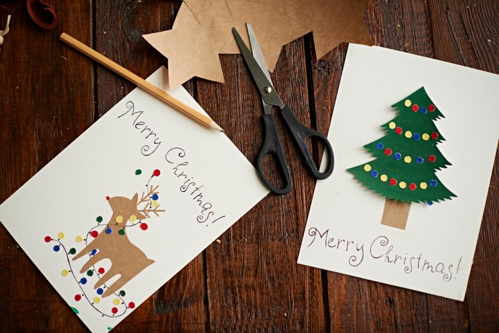 Reindeer and Christmas tree cards are sitting on a table.