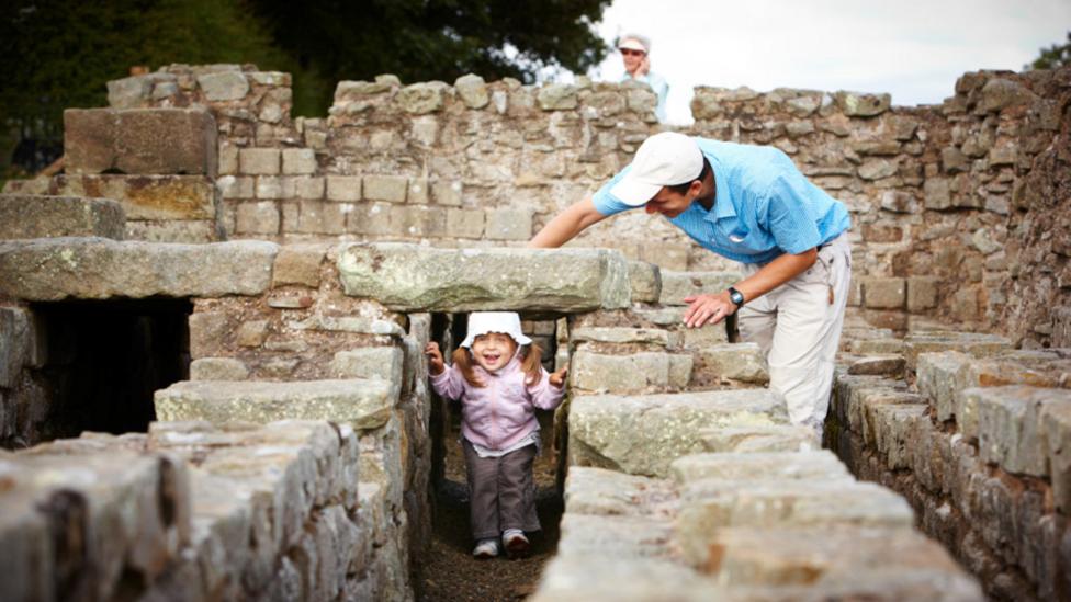 A father watching his daughter play in the ruins of the roman town