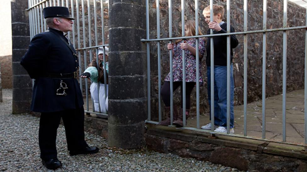 Victorian policeman watching over a young boy and two girls behind bars