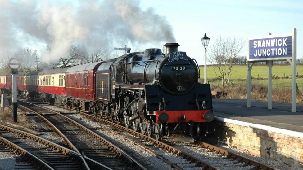 A large black and red steam train coming towards the camera