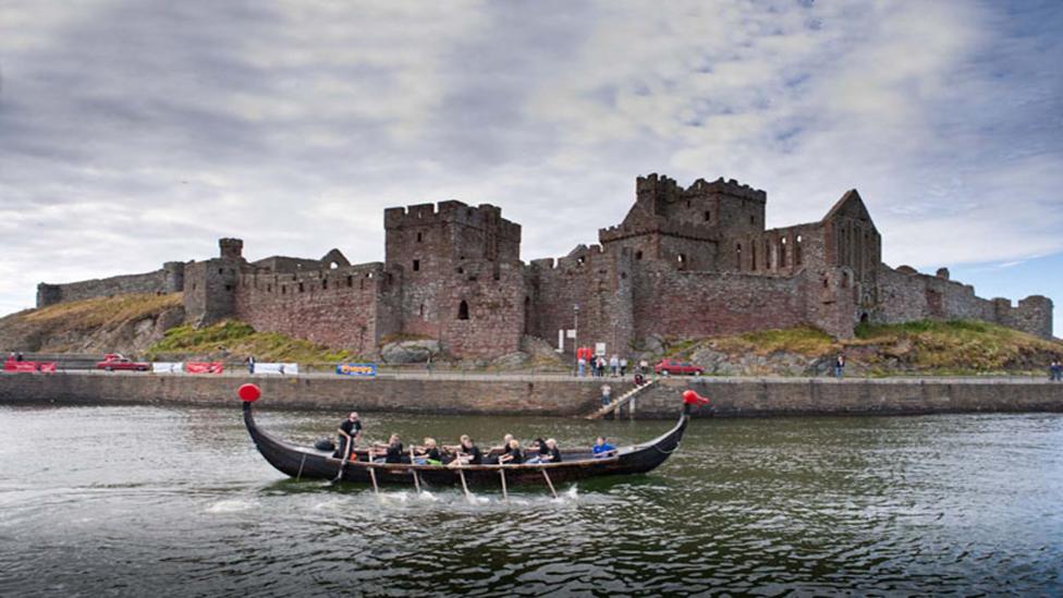 A longboat race taking place in front of Peel Castle