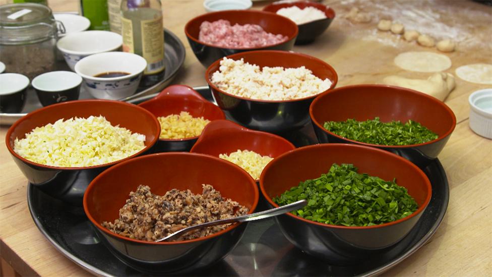 Fresh ingredients are laid out in black and red Chinese bowls.