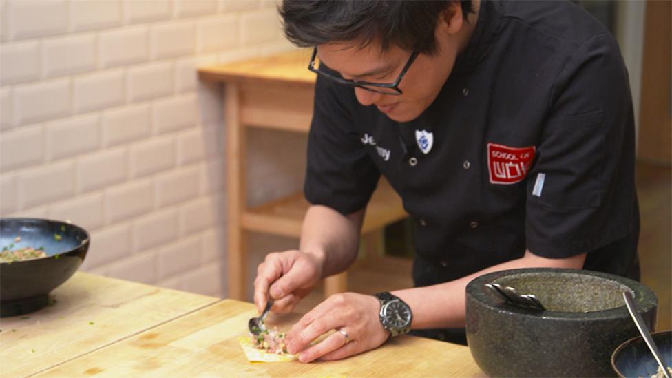 Jeremy Pang from School of Wok fills the wonton pastry on a kitchen table.