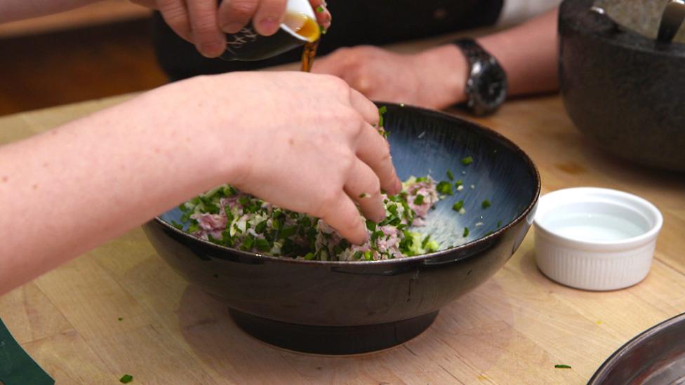 Close up of hands mixing the filling ingredients for the wonton recipe.