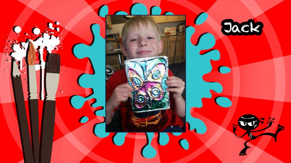 A photo of a boy holding a homemade butterfly art picture.