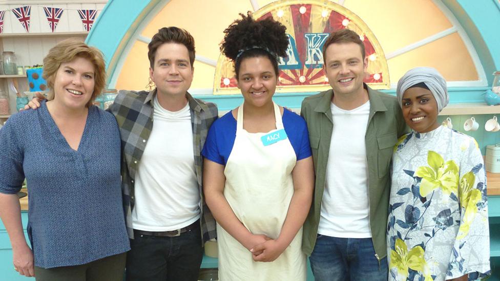 A young girl called Macy stands in the Bake Off tent with judges Allegra and Nadiya and Sam and Mark.