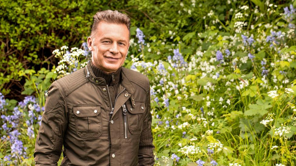 A man standing in a field filled with flowers.