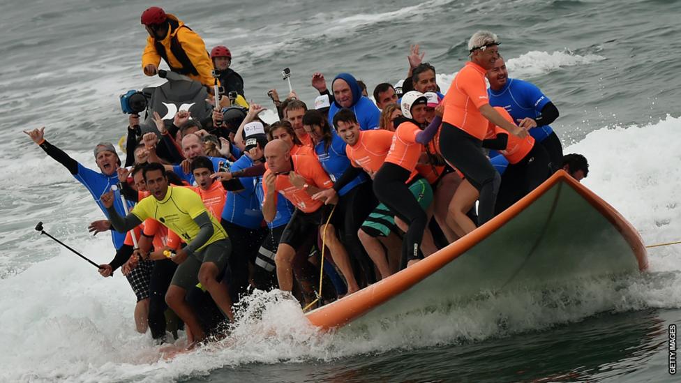 A crowd of people on a huge skateboard.