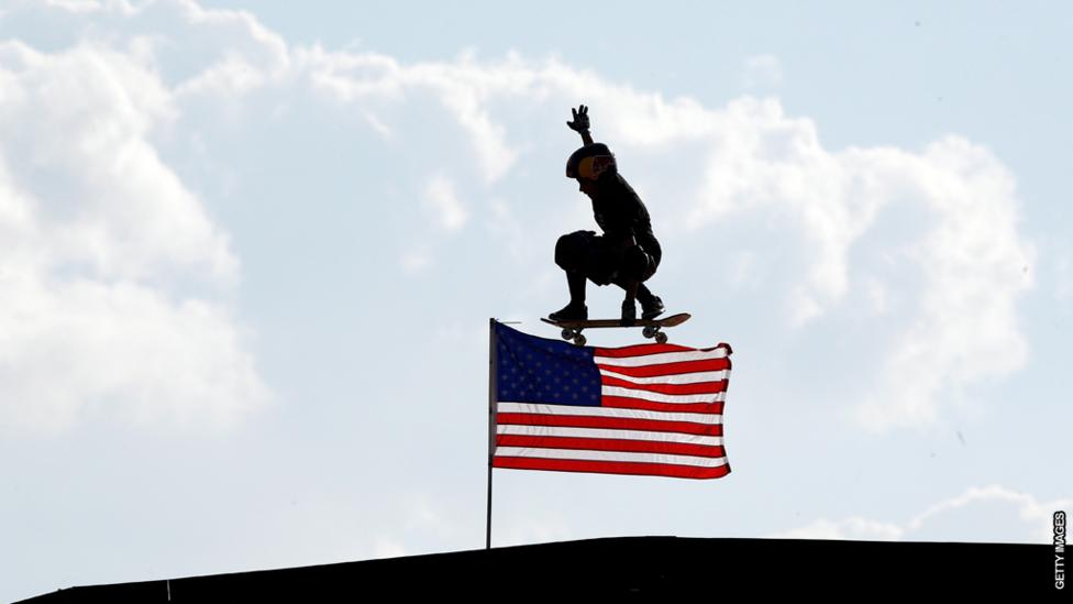 A boy skateboarding over an American flag.