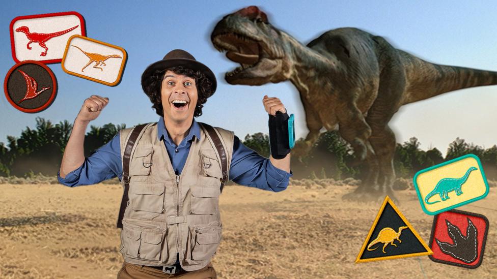 Andy from Andy's Dinosaur Adventures points behind at a large dinosaur in the background. He is surrounded by dinosaur badges to collect in the game.