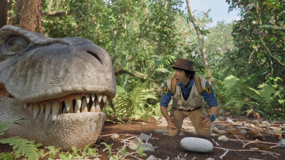 Andy looks at a dinosaur egg in a nest.