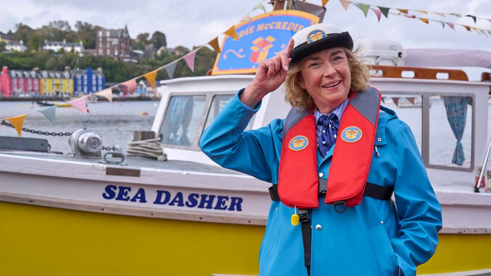 Edie McCredie pose in a sailor outfit outside her boat in the Balamory harbour.