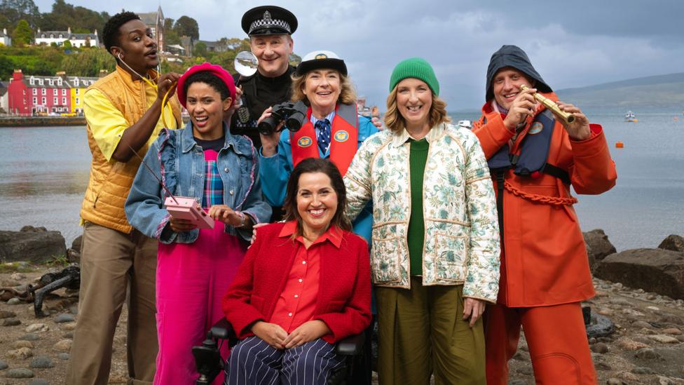 The residents of Balamory posing and smiling by the harbour.