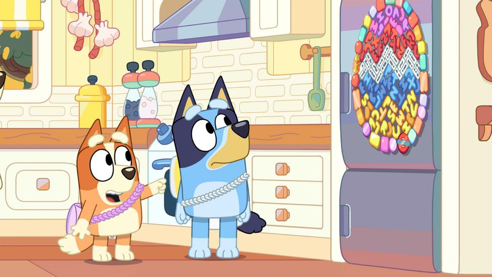 Bluey and Chilli look at a fridge with an Easter egg decoration on the front.