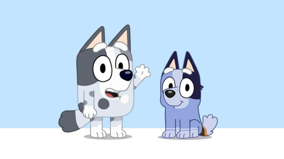 Two cartoon puppies, one grey and black, one blue and black. The grey puppy stands on hind legs and waves with a front paw, smiling. The blue puppy is sitting on his hind legs front paws placed neatly in front.