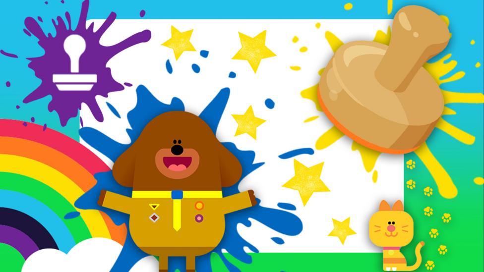 A large stamp splat, yellow paint stamps in star-shapes on a canvas. Hey Duggee and Enid the yellow cat smiling and making a mess.