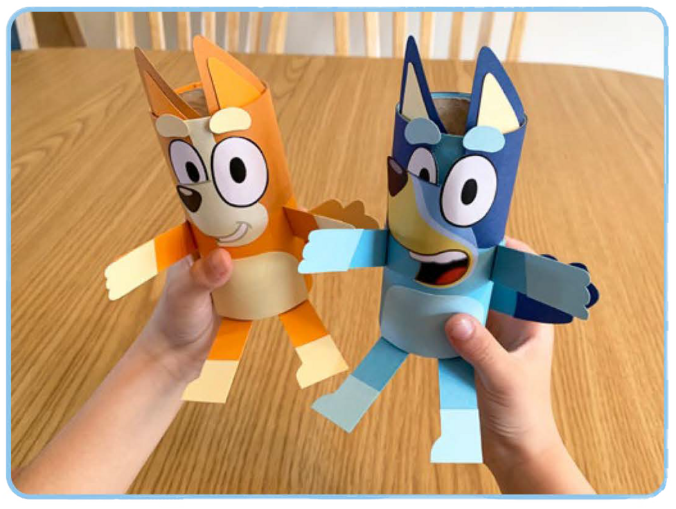 Person holding Bluey and Bingo characters made from recycled paper tubes and coloured paper
