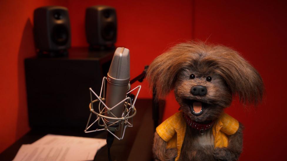 Dodge in a radio studio with a microphone