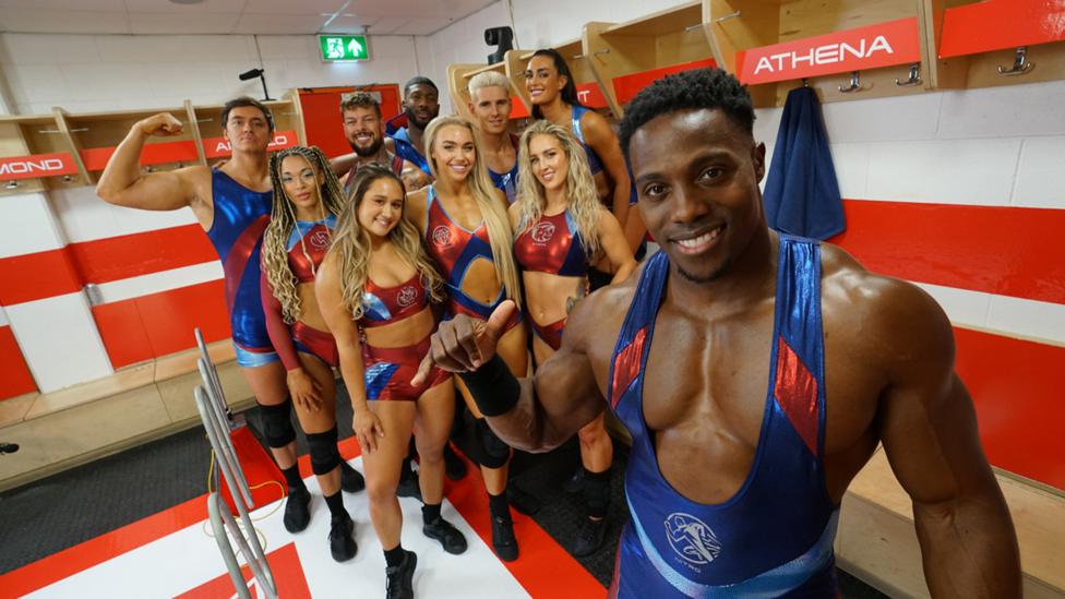 Characters from Gladiators pose in gym gear inside a dressing room