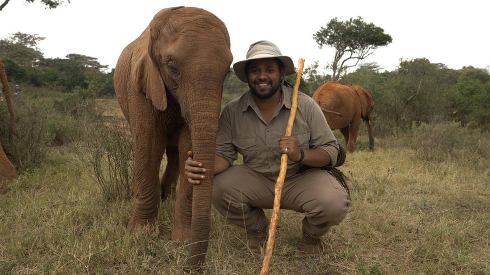 Hamza poses alongside a baby elephant in Africa.