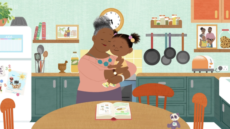 Gran Gran embraces JoJo in her arms as they stand in the kitchen, cooking up something that needs a little bit of love.