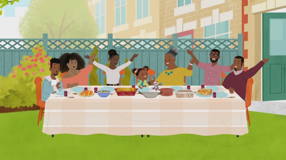 Image of a family celebrating Easter sitting around a large table in a garden with food on.