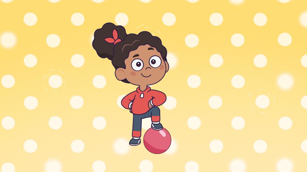 Ruby, Rafi's friend, poses with her foot on a football, arms on her hips, ready to play. Her bushy dark hair is tied up into an bun and her red hoodie matches her grey and red trousers, like a jogging outfit.