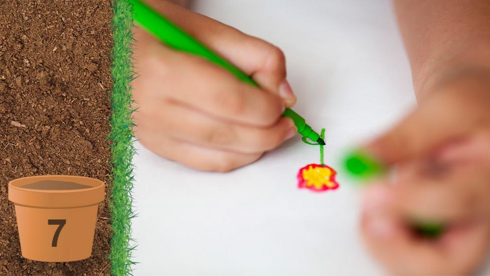 A close up of a childs hands as they colour in a drawing of a flower