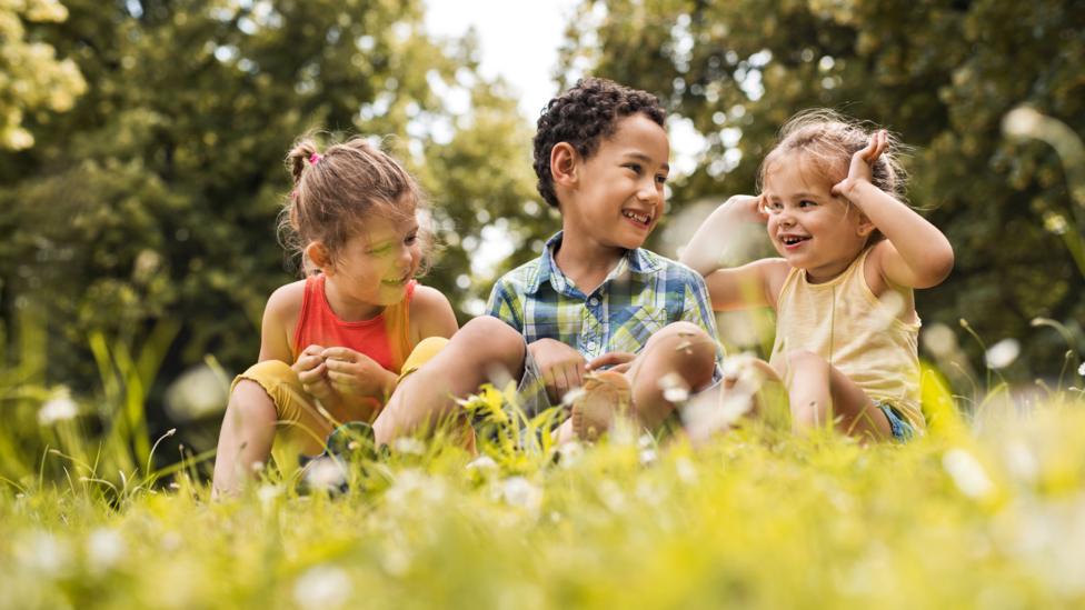 Three kids sat outside having fun together