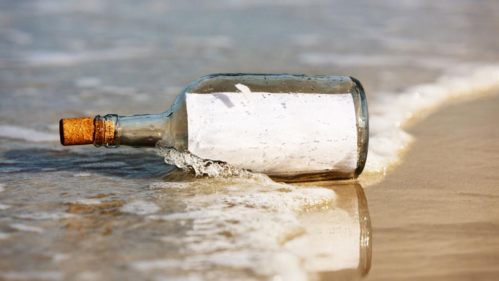 A glass bottle with a message inside on a beach