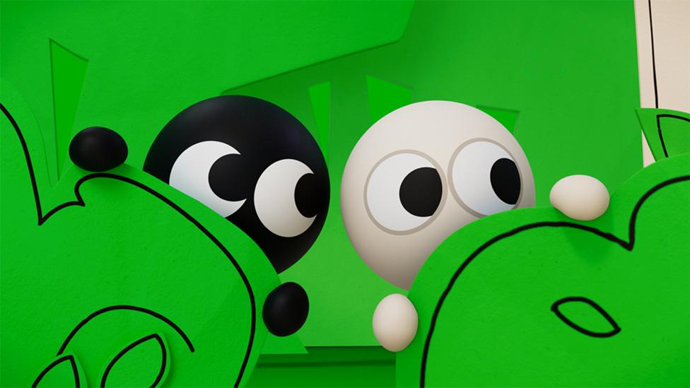 Black and White peep out from behind a green hedge.