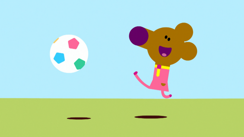 A cartoon mouse is kicking a football on a field