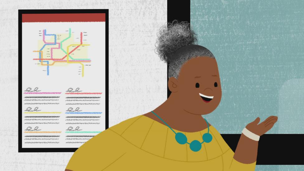 Gran Gran, wearing a yellow top and a blue necklace, talking in front of a Tube map