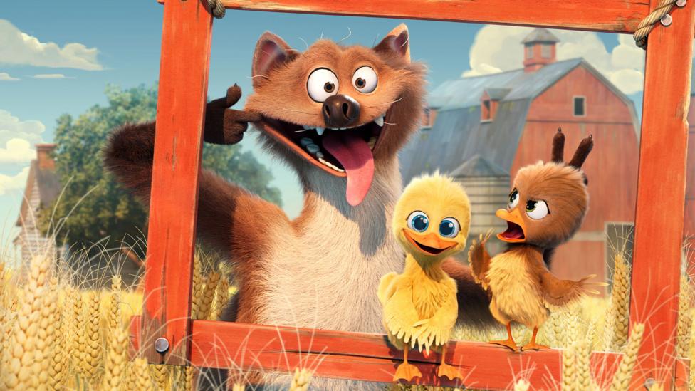 A weasel poses for a photo pulling a funny face with two chicks. A yellow chick is smiling for the photo, but the brown chick looks cross.They are stood with a hanging red picture frame in front of them.
