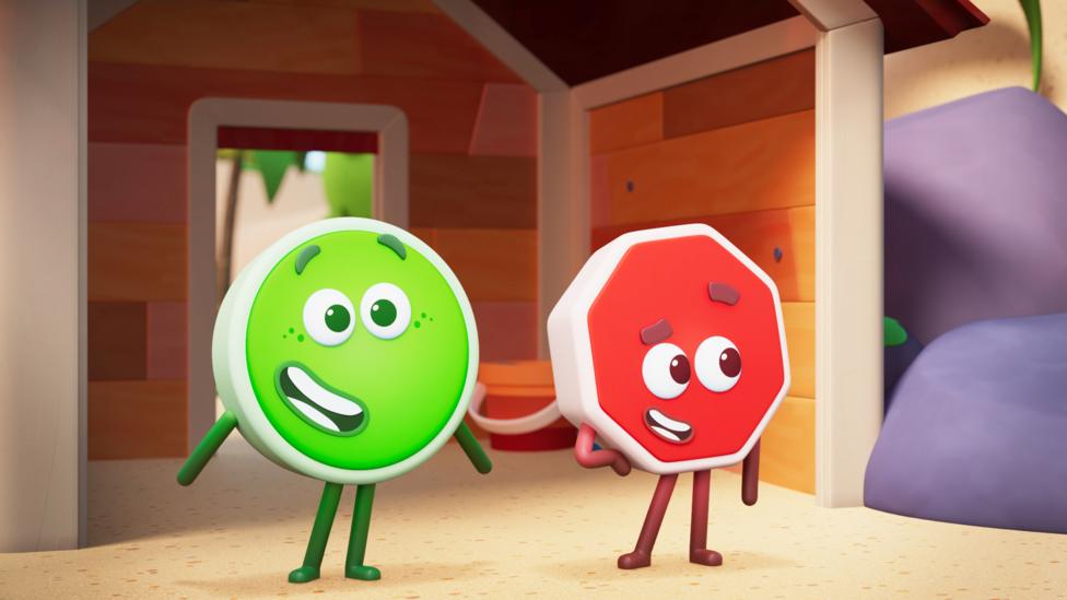 Green Go and red Stop standing in front of a small timber house in Wonderblocks