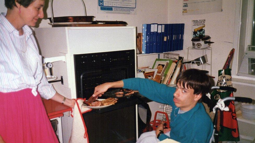 A wheelchair user getting food off a plate a woman is offering to him