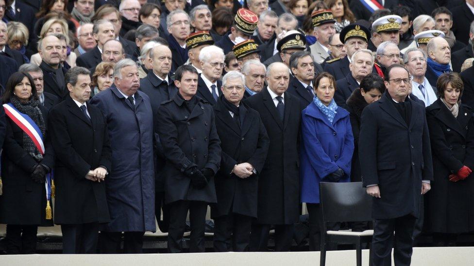 French President Francois Hollande (R) stands in front of members of the French government, officials and guests