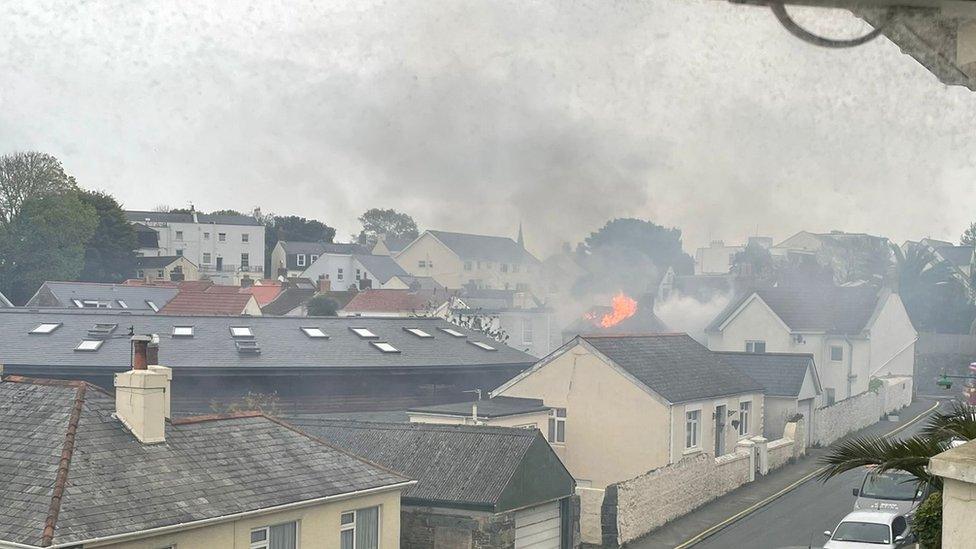 Flames and smoke coming from roof of house