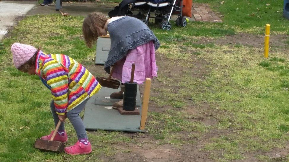 Two children try to lift trugo mallets at a club in Melbourne's Yarraville