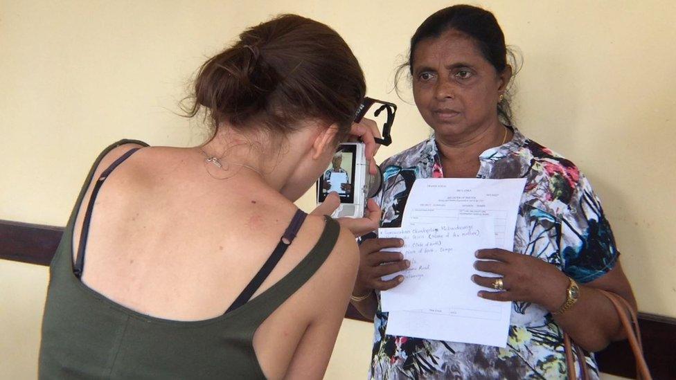 A woman photographs an estranged mother holding up her details for Facebook