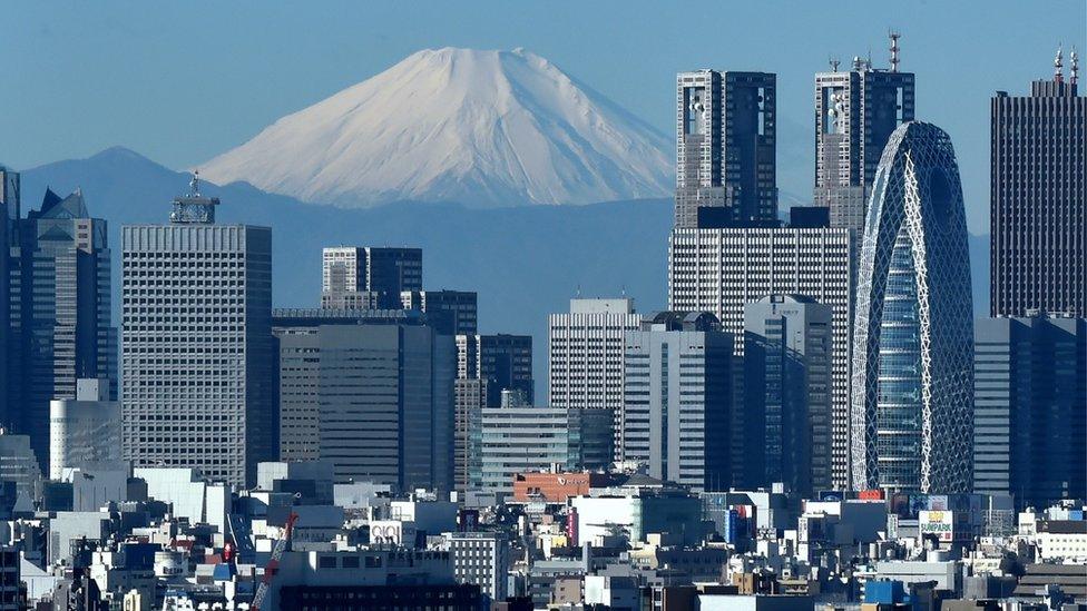 Japan's highest mountain, Mount Fuji (C) is seen behind the skyline of the Shinjuku area of Tokyo on December 6, 2014.