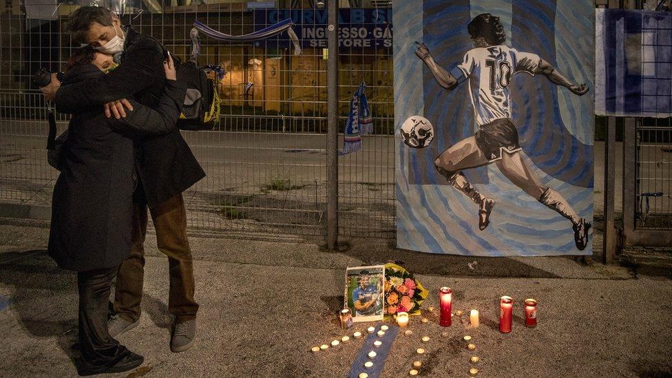 People hug each other after the death of the Argentine soccer legend Diego Maradona outside San Paolo stadium in Naples, Italy